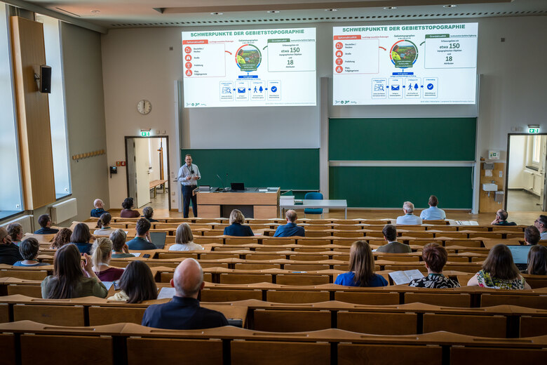 Nikola Bešlić bei seinem Vortrag „Jenseits des Luftbildes – wie Gebietstopographie die kartographische Aussagekraft des BasisDLM sichert“